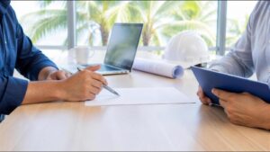 Dos socios de una empresa de construcción revisan un acuerdo en una mesa de oficina luminosa en Florida.